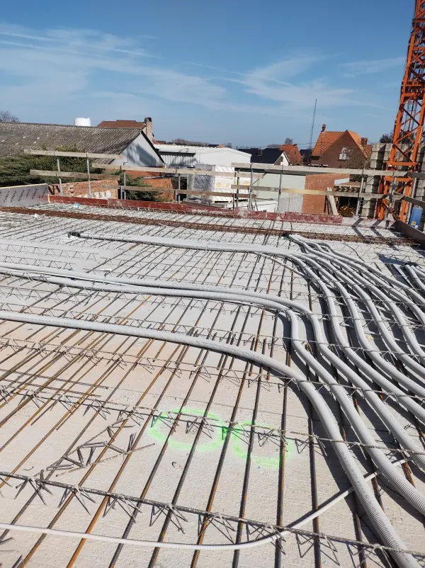 Grijze ventilatieleidingen op de wapening van een verdiepingsvloer in ruwbouw, vóór het storten